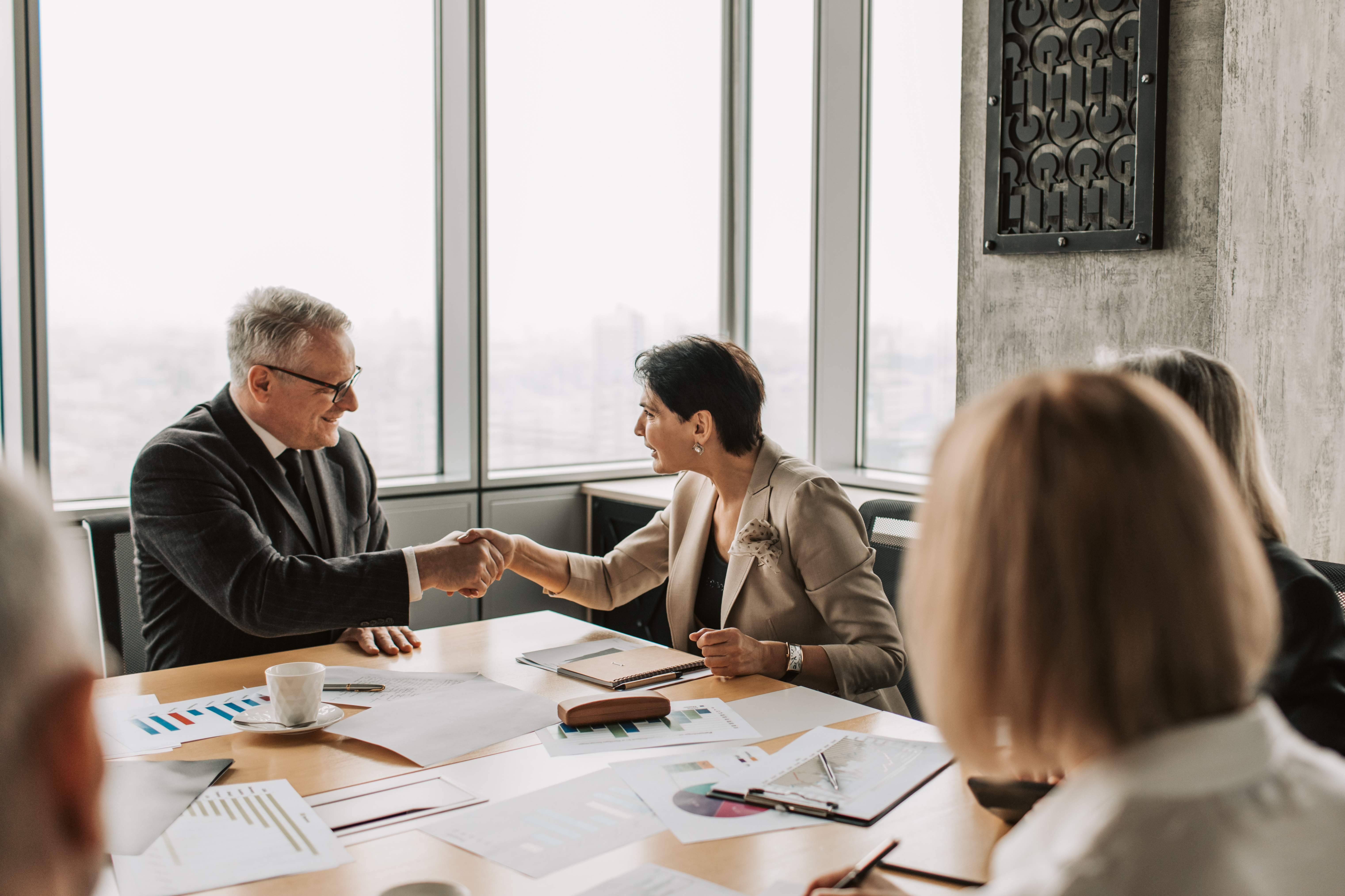 Two people shaking hands across a table