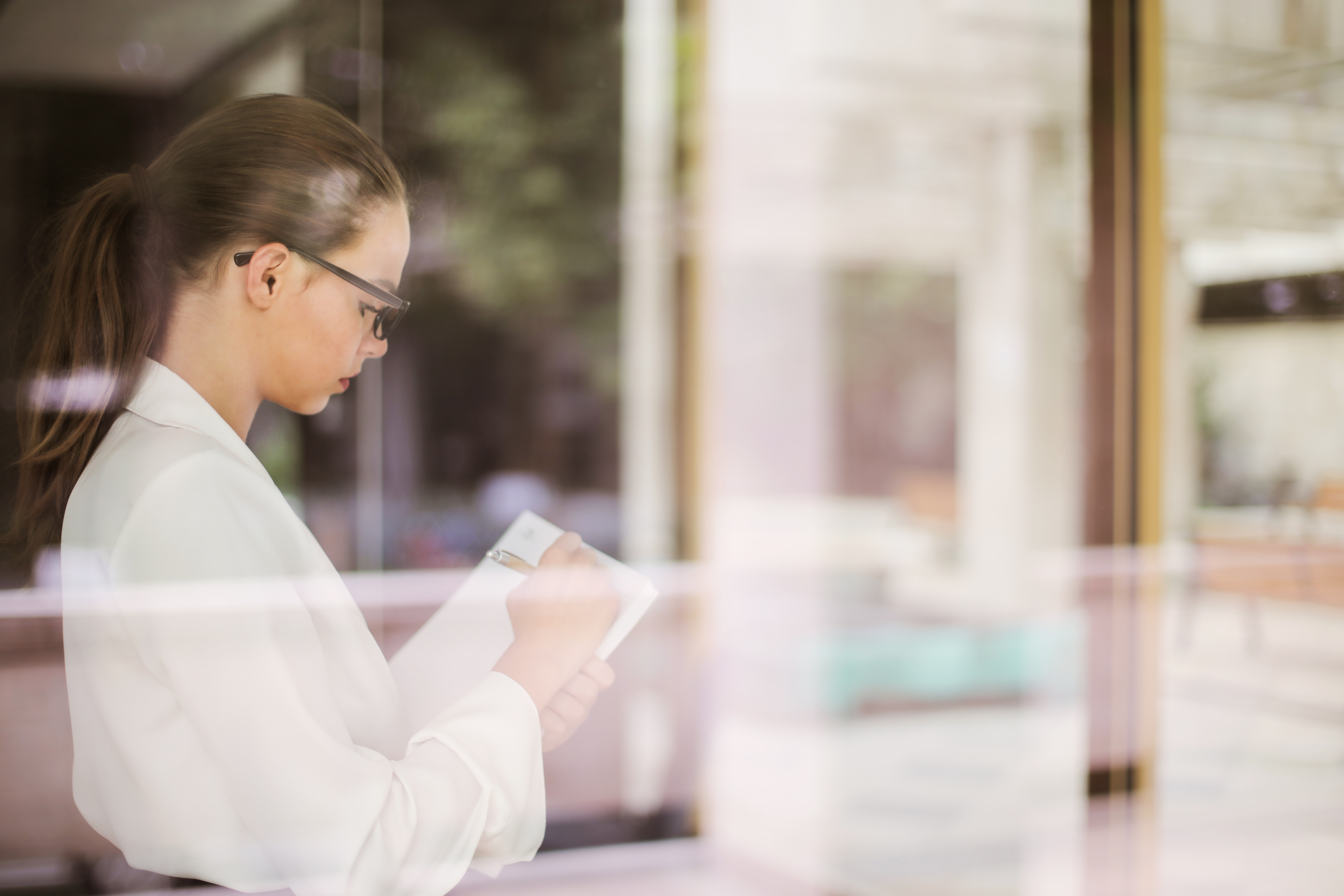 Woman standing up and taking notes in her notebook