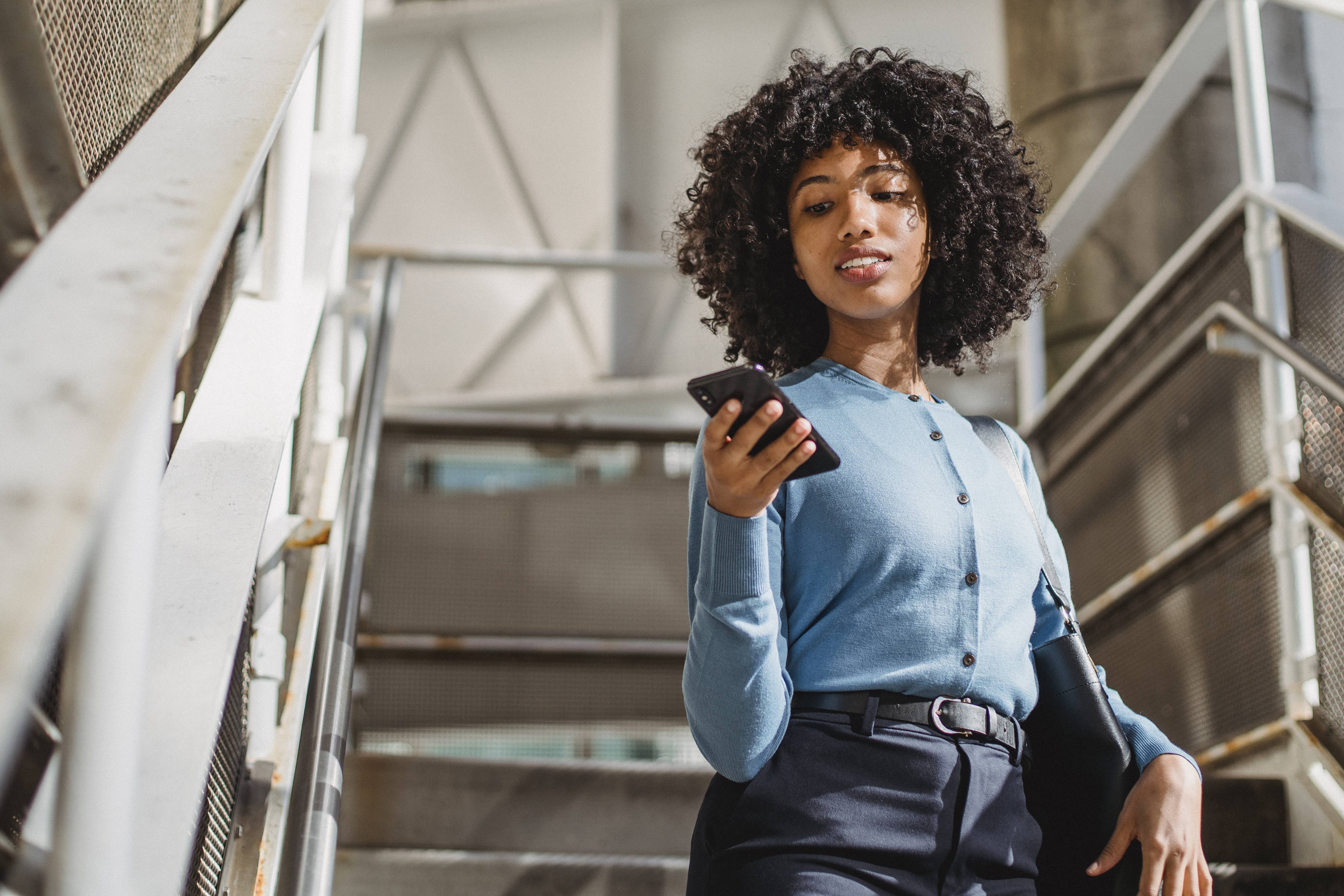 Woman walking down the stairs with a phone in her hand