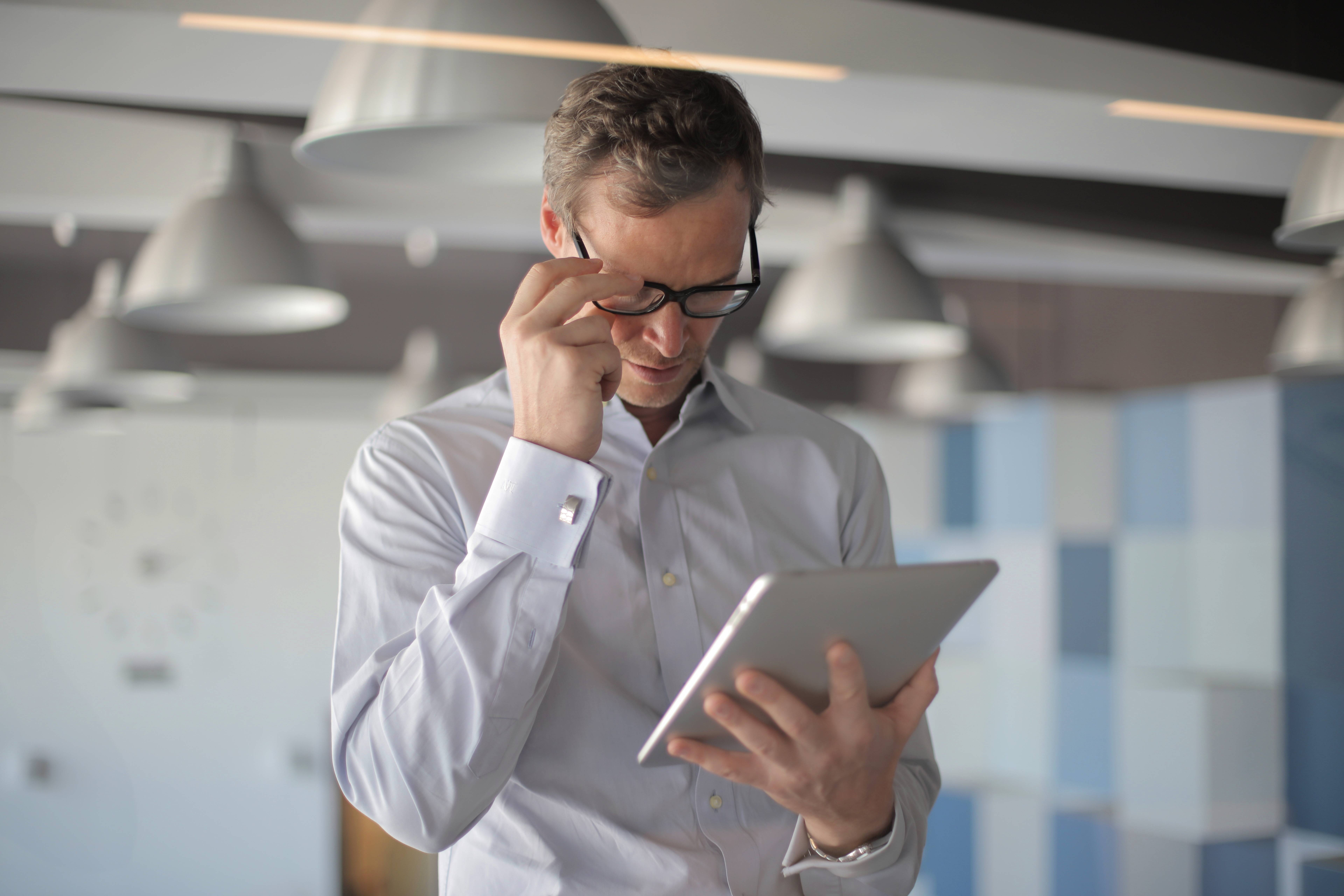 Man with glasses looking at a tablet